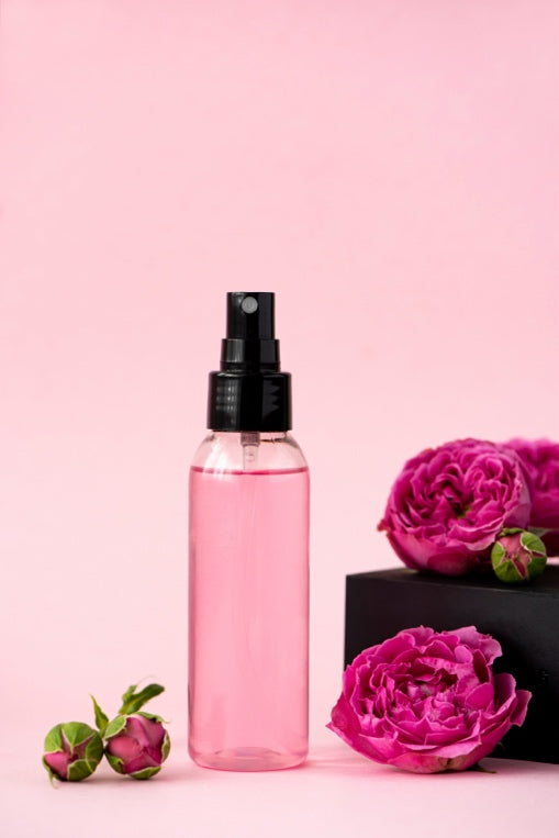 A bottle of Rose Water next to flowers.