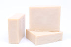 Pale pink goat milk soap bars stacked together.